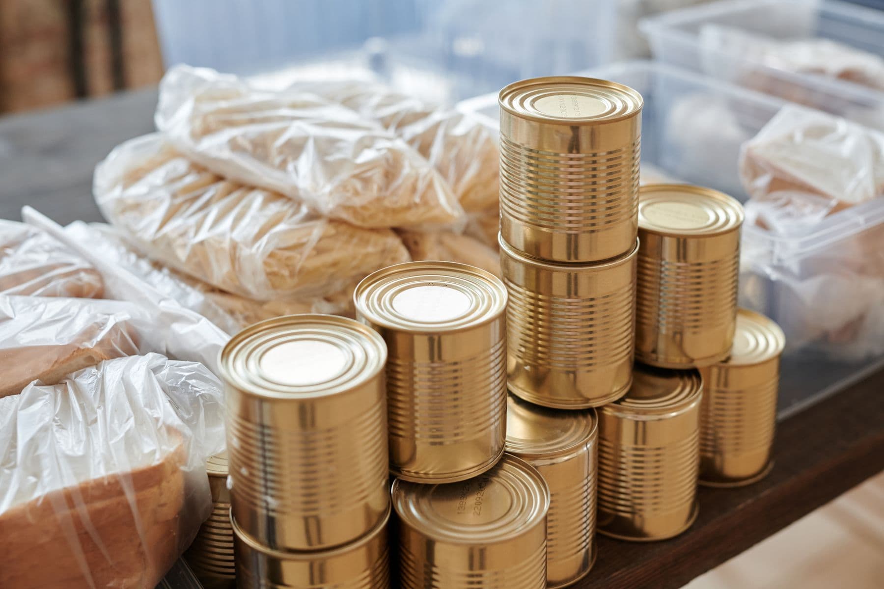Stacked tins of food beside bagged bread, sorted ready for distribution.