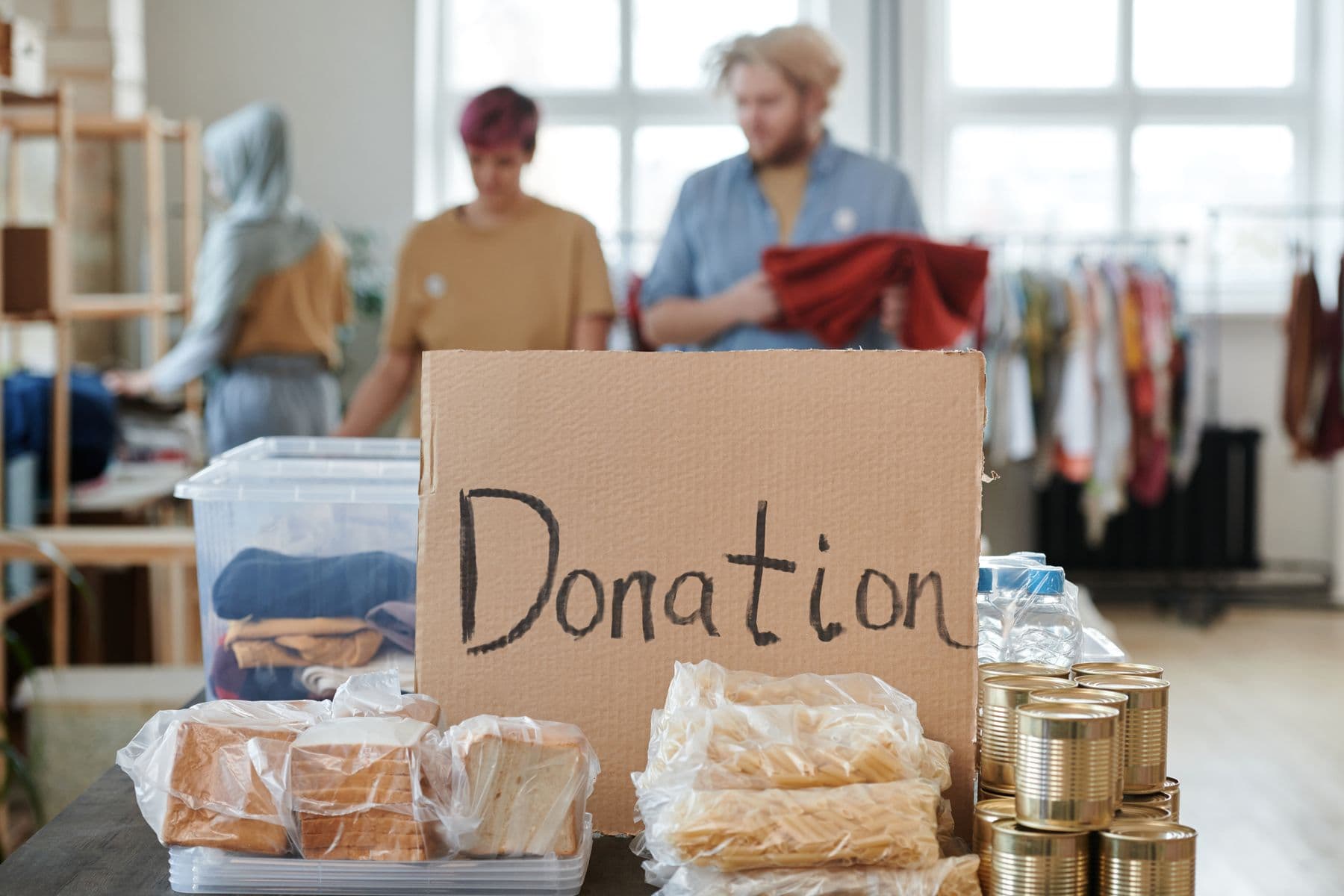 A hand-lettered cardboard sign reading Donation, propped on a table of bagged bread and folded clothing.