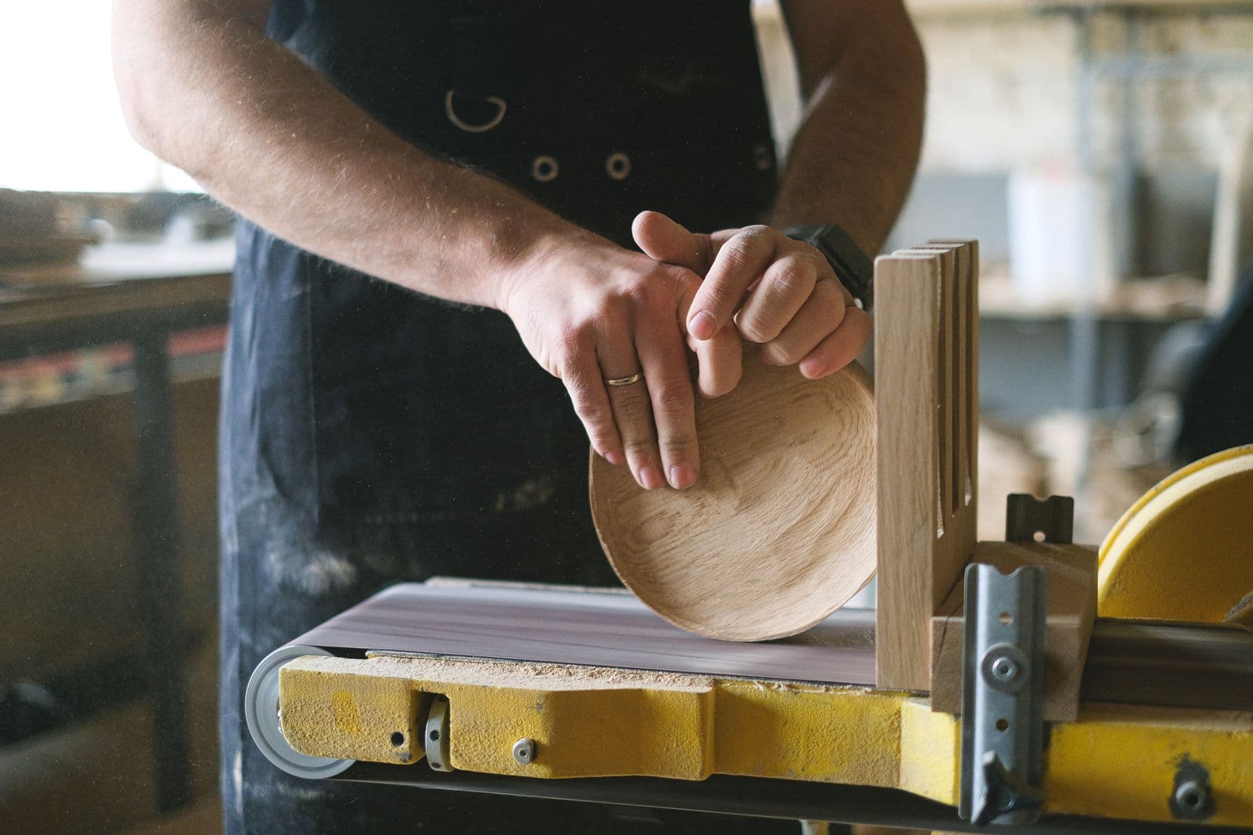 Hands guiding a piece of timber through a workshop machine.